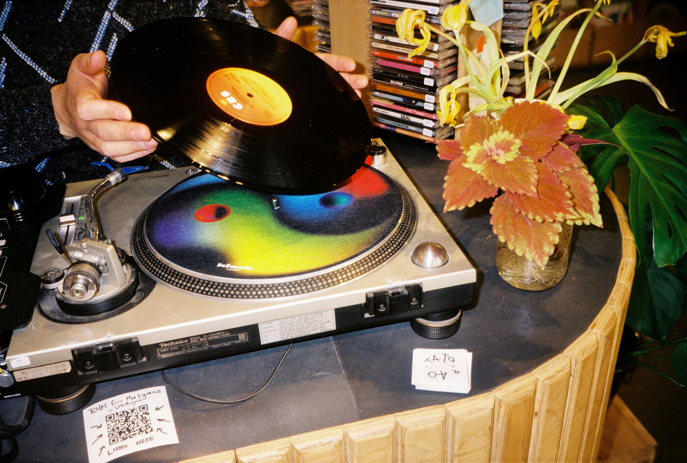 Hands holding a vinyl record above a turntable slipmat at 72records